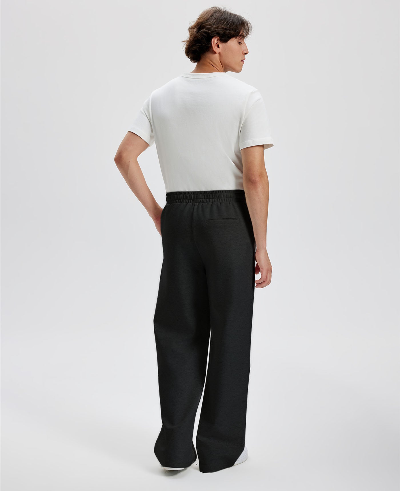 Cotton black sweatpants for men, back view. Elastic waistband and back pocket.