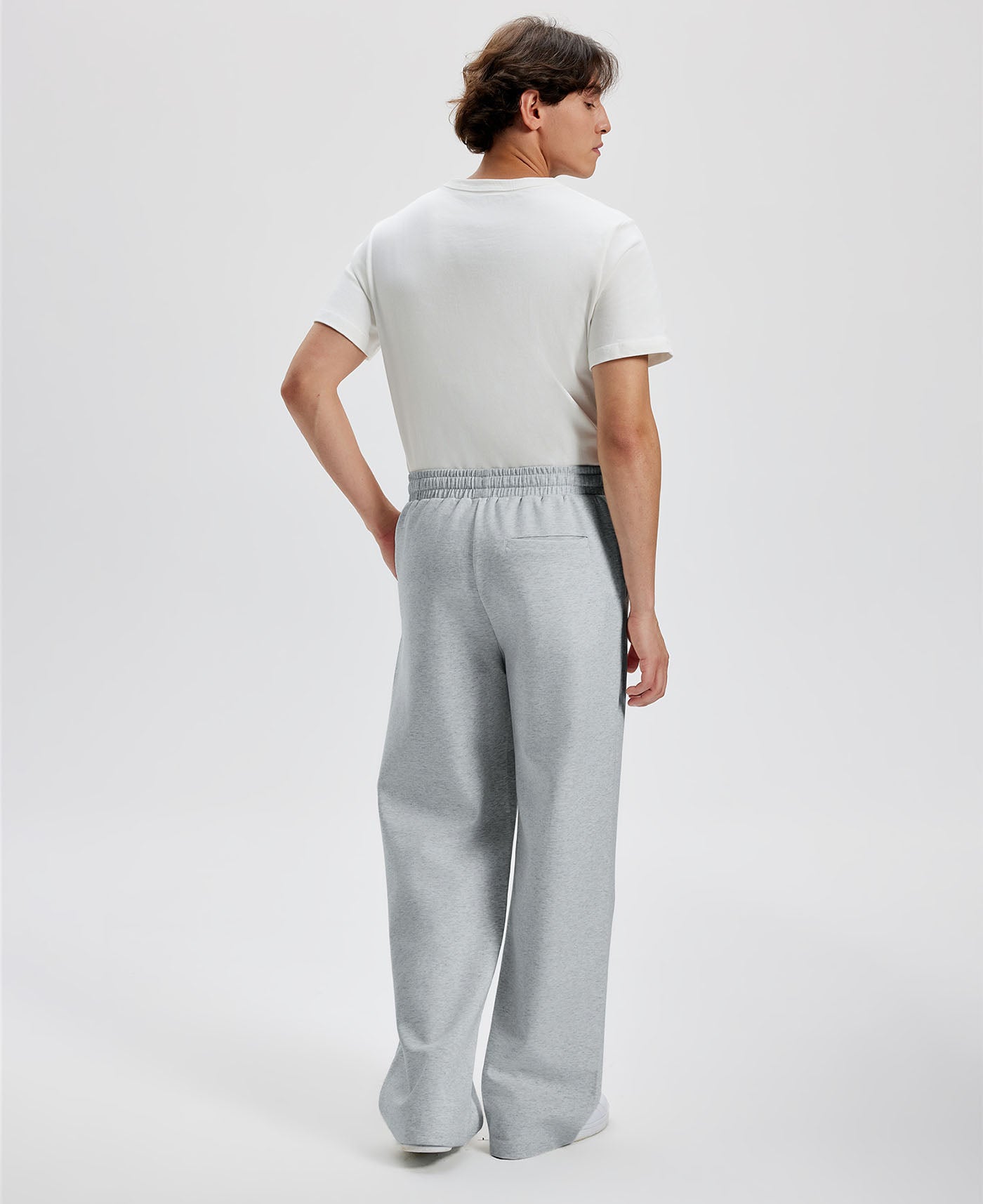 Cotton light grey sweatpants for men, back view. Elastic waistband and back pocket.