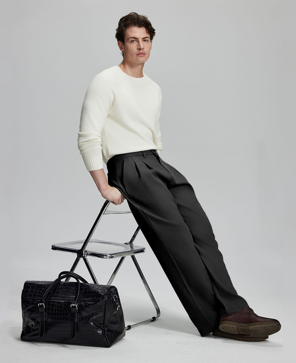Styled with white sweater and black bag, leaning on chair¡ªelegant yet relaxed look in men¡¯s black baggy pleated dress pants.