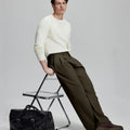 Styled with white sweater and black bag, leaning on chair¡ªelegant yet relaxed look in men¡¯s coffee baggy pleated dress pants.