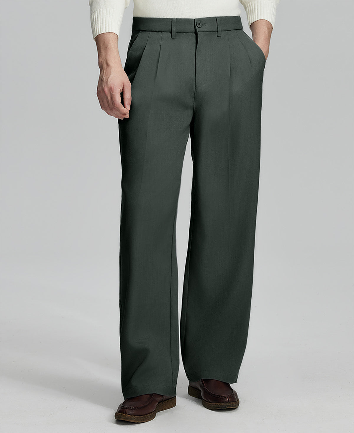 Man in white knit, dark grey wide-leg dress pants and brown shoes¡ªhand in pocket showing pleated front and fluid drape.