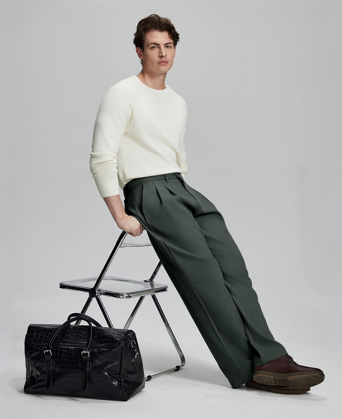Styled with white sweater and black bag, leaning on chair¡ªelegant yet relaxed look in men¡¯s dark grey baggy pleated dress pants.