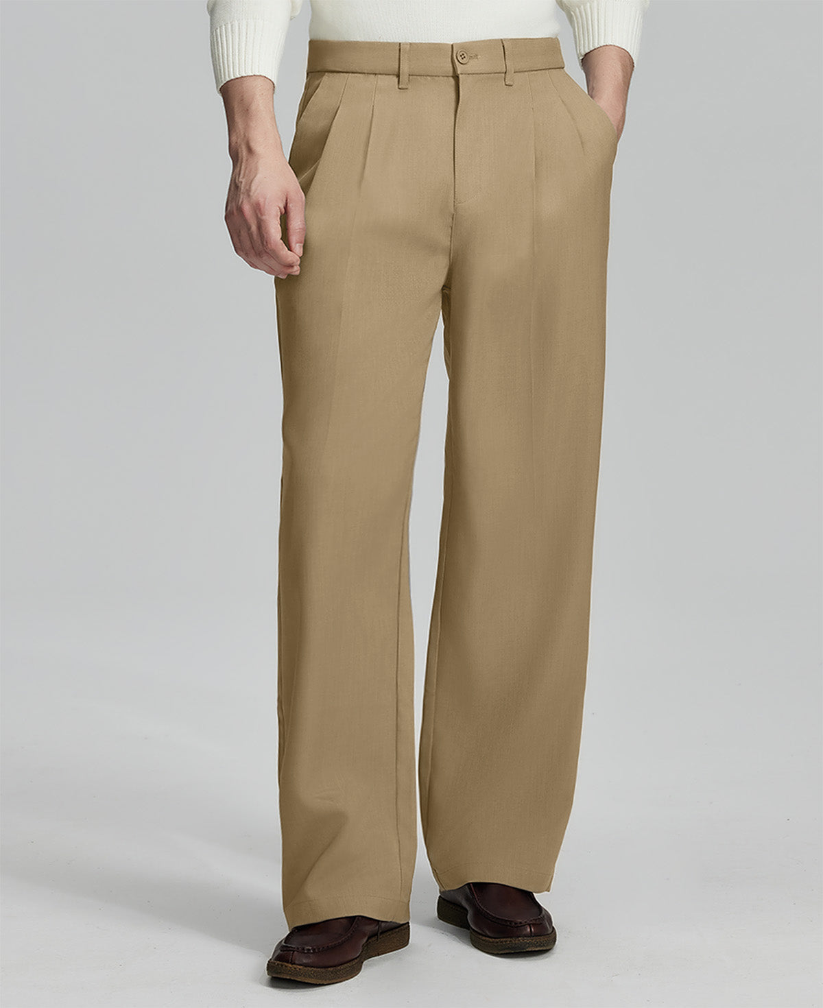 Man in white knit, khaki wide-leg dress pants and brown shoes¡ªhand in pocket showing pleated front and fluid drape.