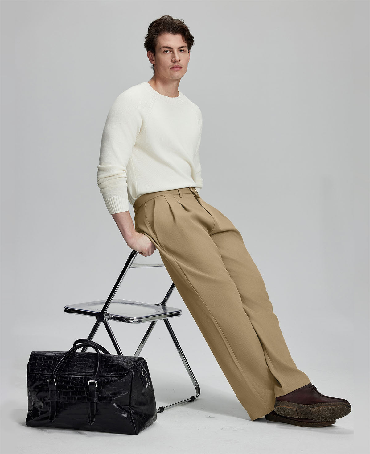 Styled with white sweater and black bag, leaning on chair¡ªelegant yet relaxed look in men¡¯s khaki baggy pleated dress pants.