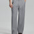 Man in white knit, light grey wide-leg dress pants and brown shoes¡ªhand in pocket showing pleated front and fluid drape.