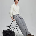 Styled with white sweater and black bag, leaning on chair¡ªelegant yet relaxed look in men¡¯s light grey baggy pleated dress pants.
