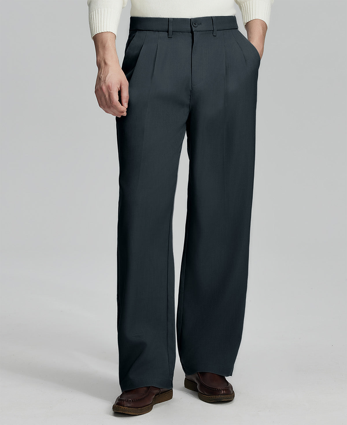 Man in white knit, navy wide-leg dress pants and brown shoes¡ªhand in pocket showing pleated front and fluid drape.