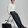 Styled with white sweater and black bag, leaning on chair¡ªelegant yet relaxed look in men¡¯s navy baggy pleated dress pants.