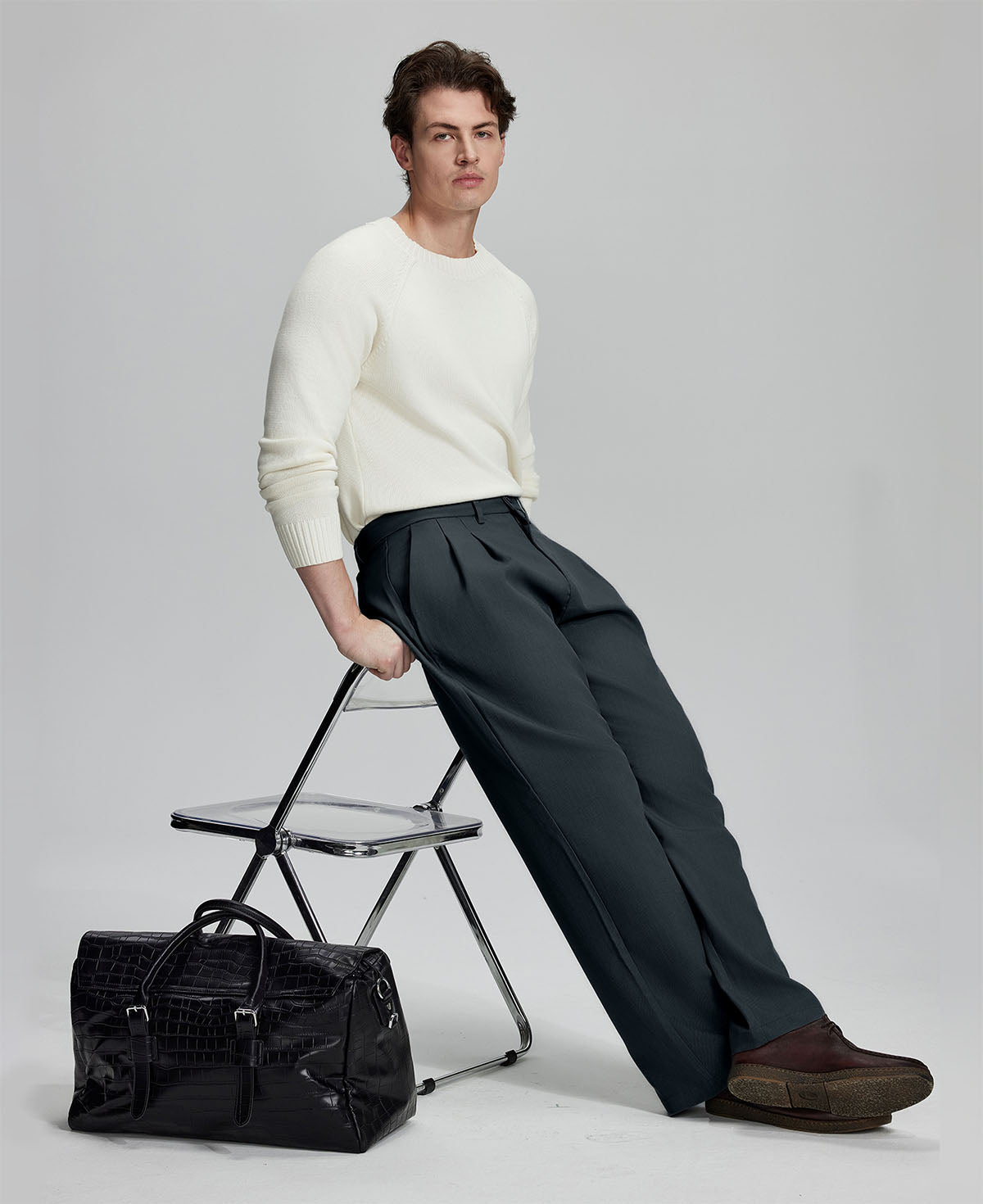 Styled with white sweater and black bag, leaning on chair¡ªelegant yet relaxed look in men¡¯s navy baggy pleated dress pants.