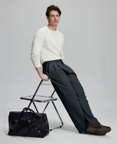 Styled with white sweater and black bag, leaning on chair¡ªelegant yet relaxed look in men¡¯s navy baggy pleated dress pants.