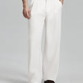 Man in white knit, white wide-leg dress pants and brown shoes¡ªhand in pocket showing pleated front and fluid drape.
