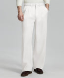 Man in white knit, white wide-leg dress pants and brown shoes¡ªhand in pocket showing pleated front and fluid drape.