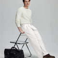 Styled with white sweater and black bag, leaning on chair¡ªelegant yet relaxed look in men¡¯s white baggy pleated dress pants.