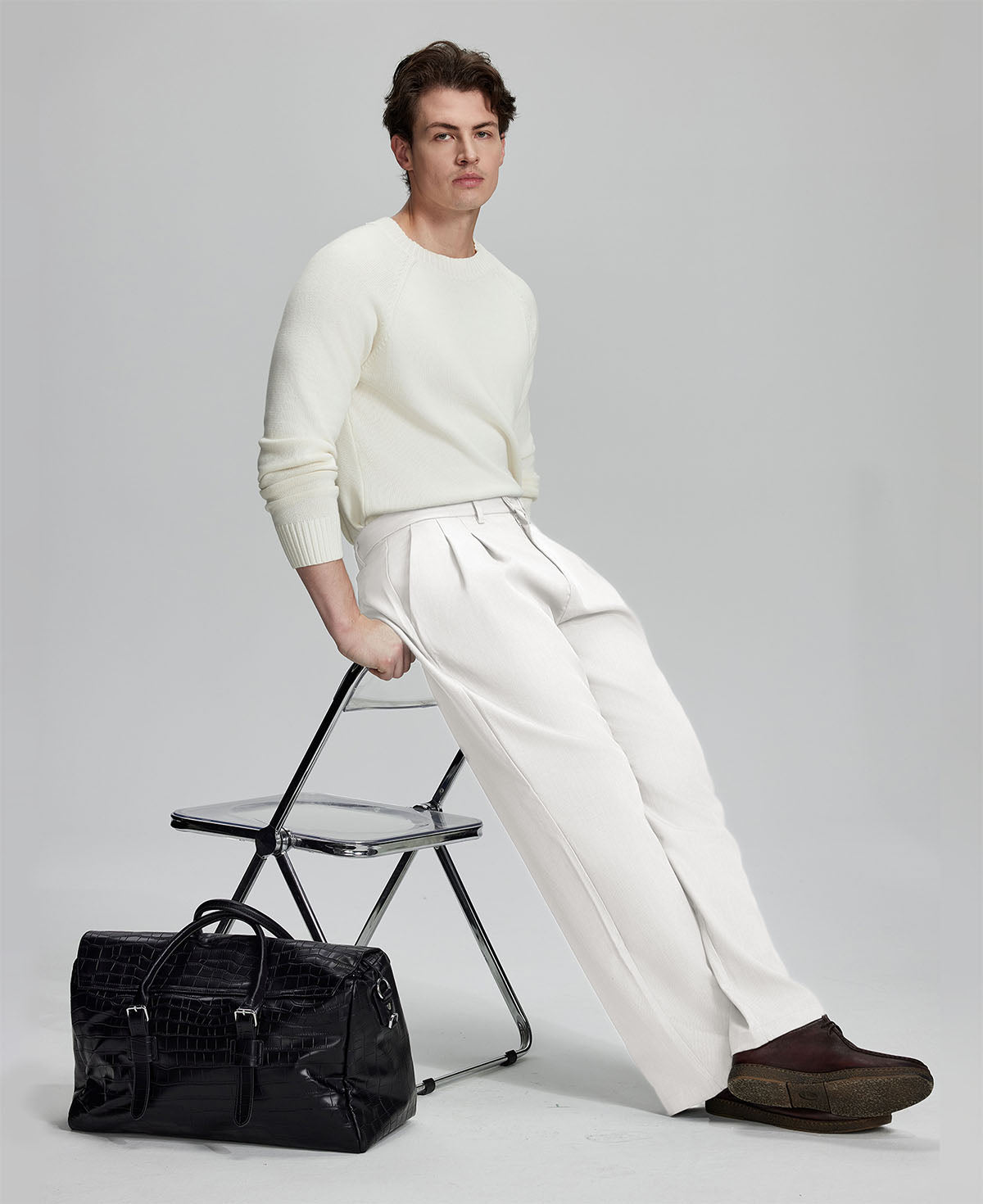 Styled with white sweater and black bag, leaning on chair¡ªelegant yet relaxed look in men¡¯s white baggy pleated dress pants.
