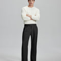Model in white sweater, black trousers & black shoes, arms crossed, presenting a smart-casual style with Baggy Pleated Dress Pants for Men.