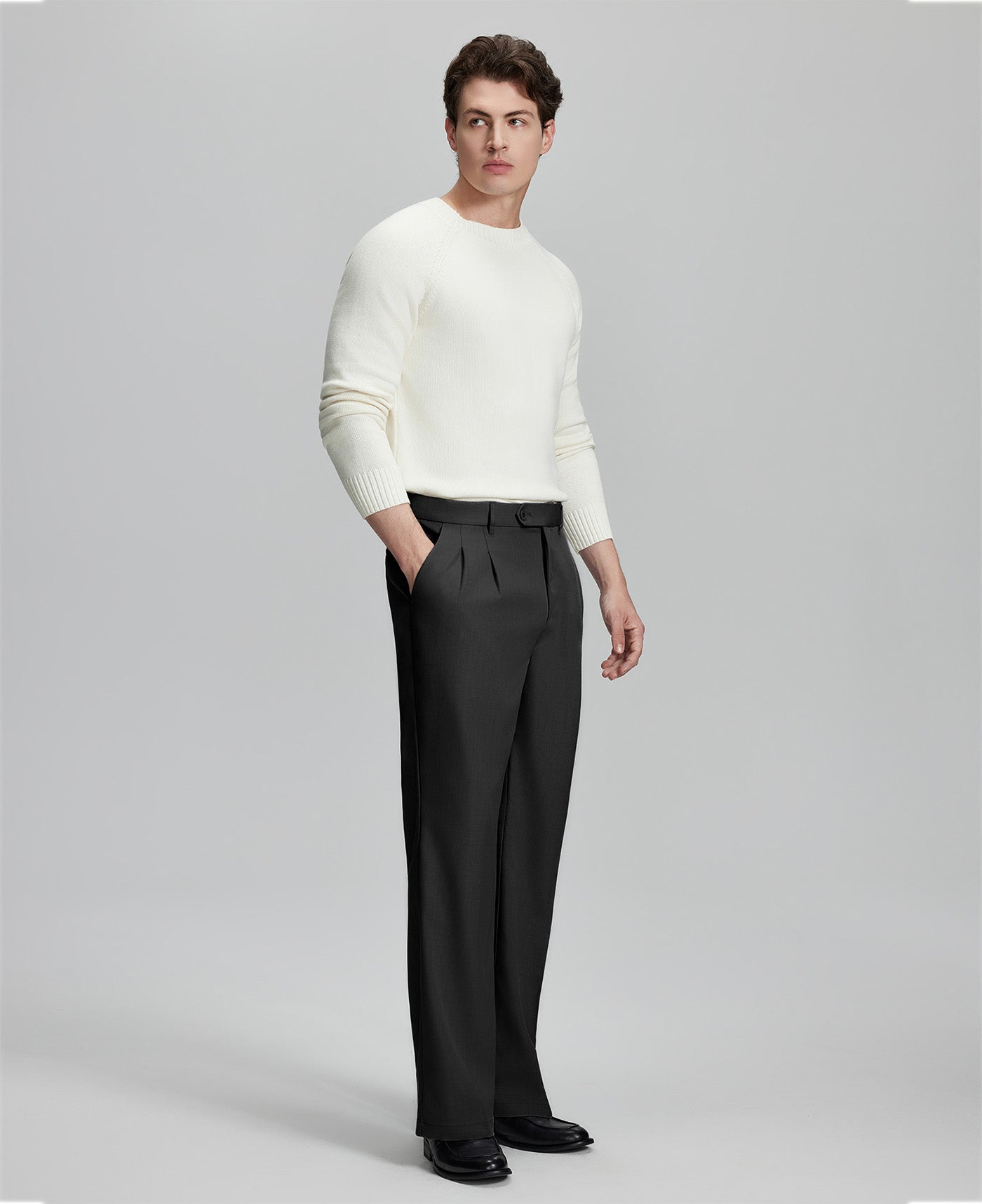 Side view of model with hand in pocket, highlighting the pleats and line of the Black Baggy Pleated Dress Pants for Men.