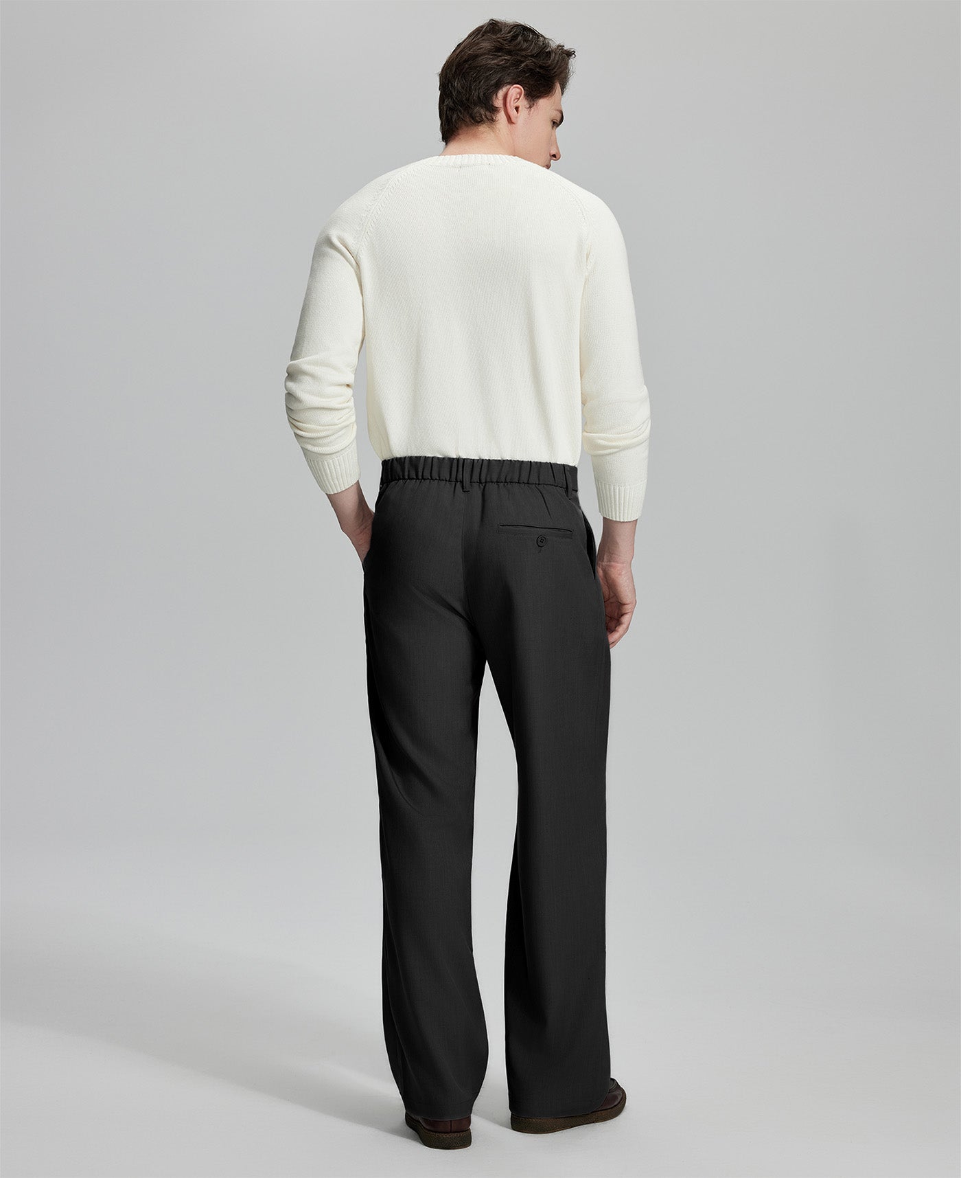 Back view of men's black dress pants showing elastic waistband and back pockets, emphasizing the silhouette of Extended Tab & Inner Drawstring design.