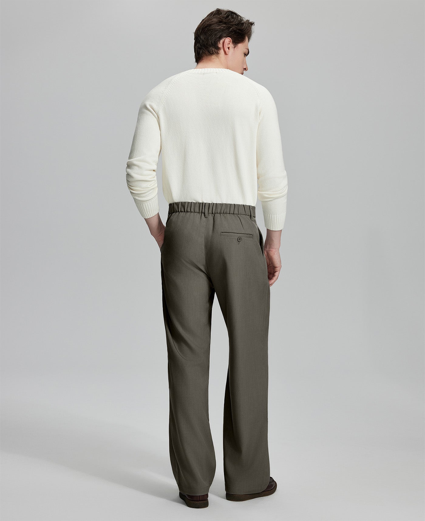 Back view of men's brown dress pants showing elastic waistband and back pockets, emphasizing the silhouette of Extended Tab & Inner Drawstring design.