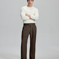 Model in white sweater, coffee trousers & black shoes, arms crossed, presenting a smart-casual style with Baggy Pleated Dress Pants for Men.