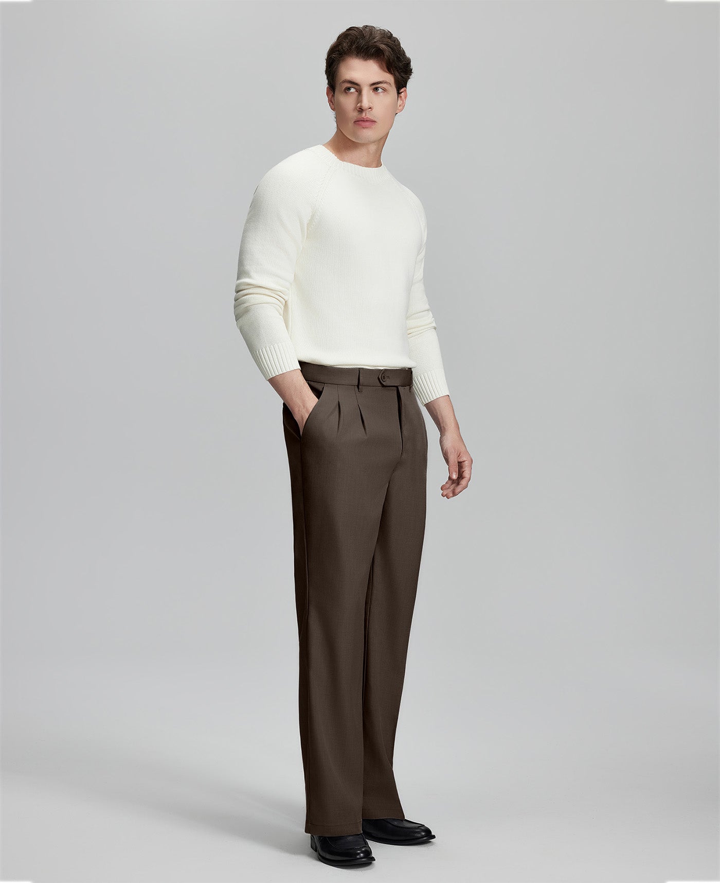 Side view of model with hand in pocket, highlighting the pleats and line of the Coffee Baggy Pleated Dress Pants for Men.
