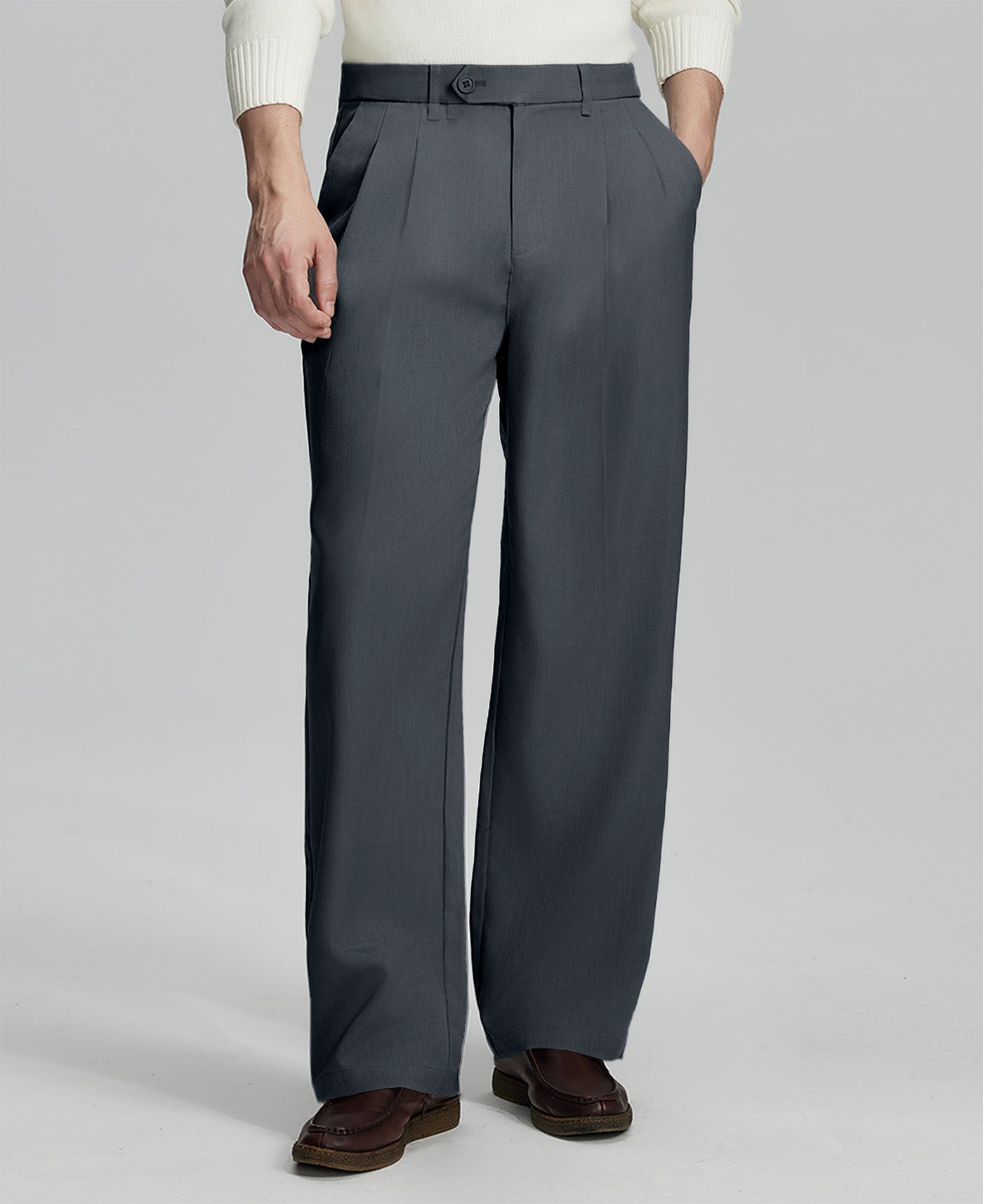 Man in white sweater, dark grey pleated pants & brown shoes, showcasing the wide-leg cut and drape of Baggy Pleated Dress Pants for Men.