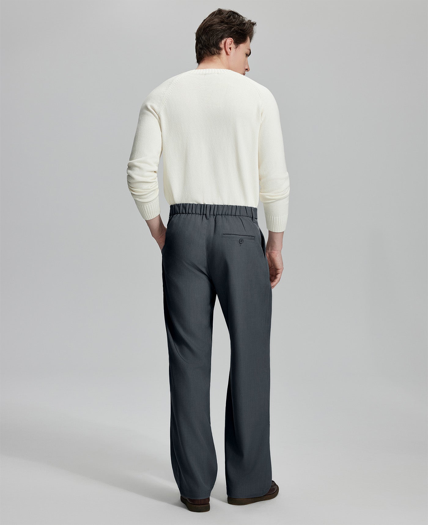 Back view of men's dark grey dress pants showing elastic waistband and back pockets, emphasizing the silhouette of Extended Tab & Inner Drawstring design.
