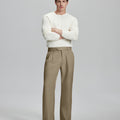 Model in white sweater, khaki trousers & black shoes, arms crossed, presenting a smart-casual style with Baggy Pleated Dress Pants for Men.