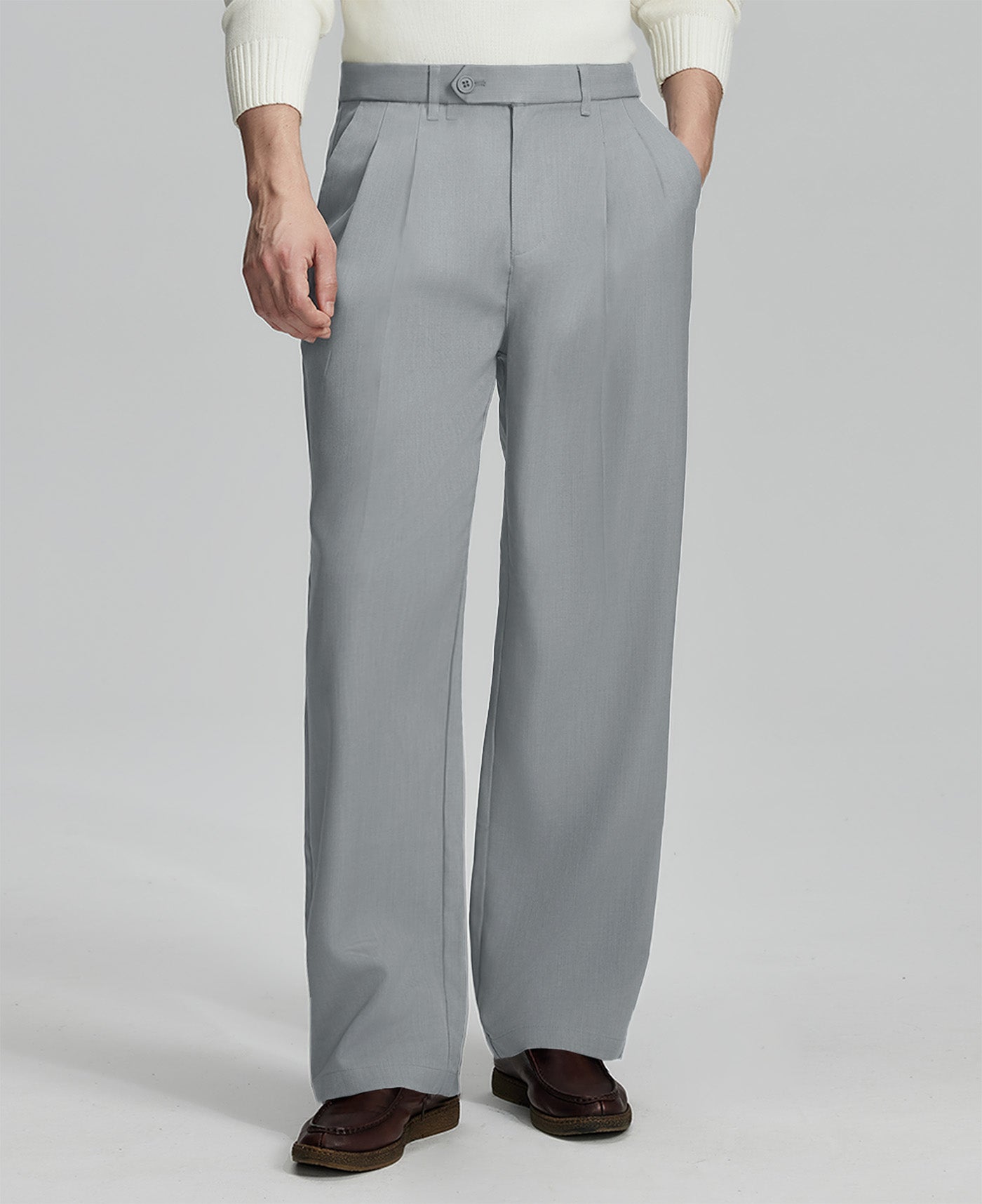 Man in white sweater, light grey pleated pants & brown shoes, showcasing the wide-leg cut and drape of Baggy Pleated Dress Pants for Men.