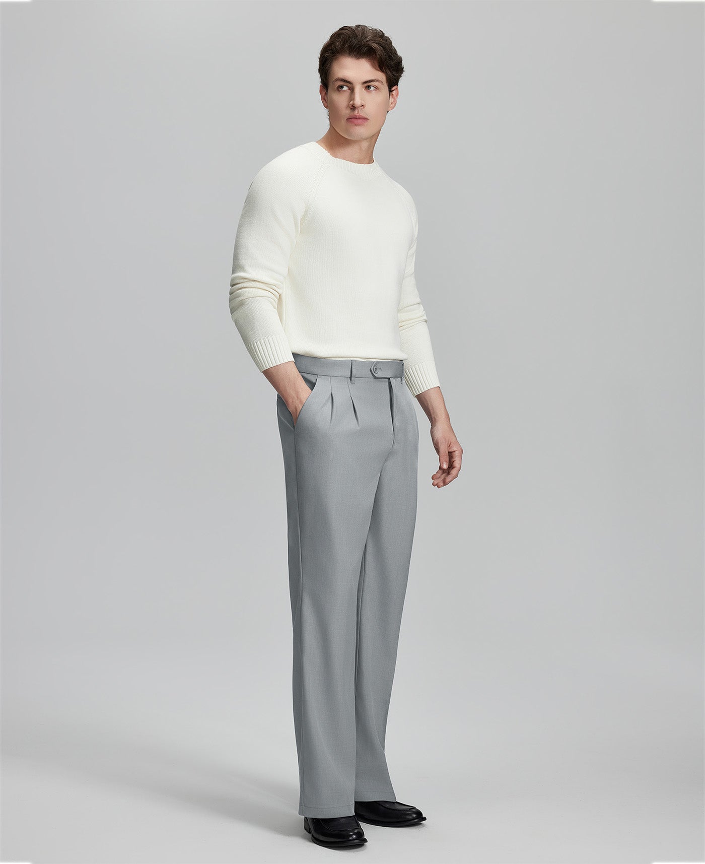 Side view of model with hand in pocket, highlighting the pleats and line of the Light Grey Baggy Pleated Dress Pants for Men.