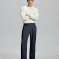 Model in white sweater, navy blue trousers & black shoes, arms crossed, presenting a smart-casual style with Baggy Pleated Dress Pants for Men.