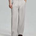 Man in white sweater, stone grey pleated pants & brown shoes, showcasing the wide-leg cut and drape of Baggy Pleated Dress Pants for Men.