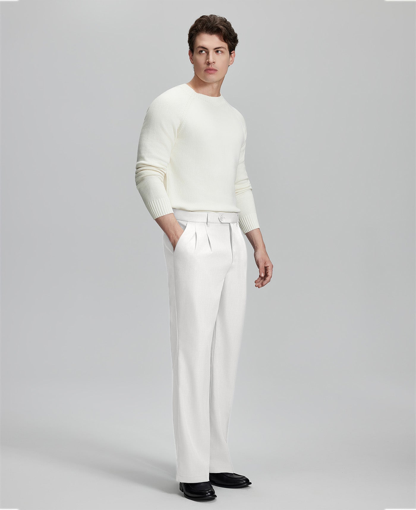 Side view of model with hand in pocket, highlighting the pleats and line of the White Baggy Pleated Dress Pants for Men.
