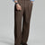 Man in light blue shirt, coffee pleated pants, and brown shoes, hand in pocket showcasing relaxed fit and drape.