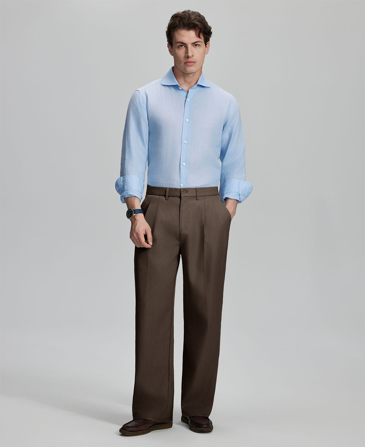 Model in light blue shirt and coffee trousers, presenting a complete outfit for a professional look.