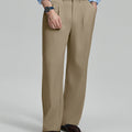 Man in light blue shirt, khaki pleated pants, and brown shoes, hand in pocket showcasing relaxed fit and drape.