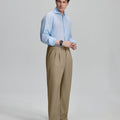 Side view of man adjusting cuff while highlighting the clean lines and casual elegance of khaki pleated baggy dress pants.