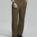 Man in light blue shirt, light brown pleated pants, and brown shoes, hand in pocket showcasing relaxed fit and drape.