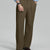 Man in light blue shirt, light brown pleated pants, and brown shoes, hand in pocket showcasing relaxed fit and drape.