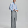 Side view of man adjusting cuff while highlighting the clean lines and casual elegance of light grey pleated baggy dress pants.