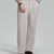 Man in light blue shirt, stone grey pleated pants, and brown shoes, hand in pocket showcasing relaxed fit and drape.