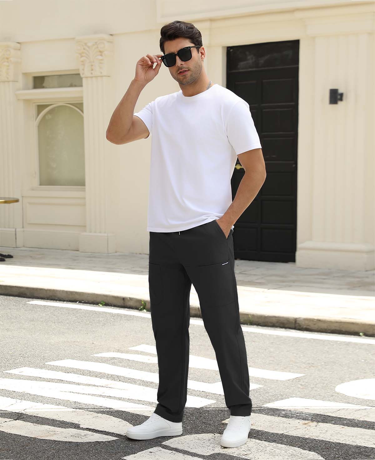 Man adjusting sunglasses, revealing side pocket details of black multipants, highlighting fit and pocket layout.