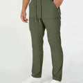 Man in green multipants with drawstring waist and multiple pockets, white sneakers, hand in pocket showing side logo.