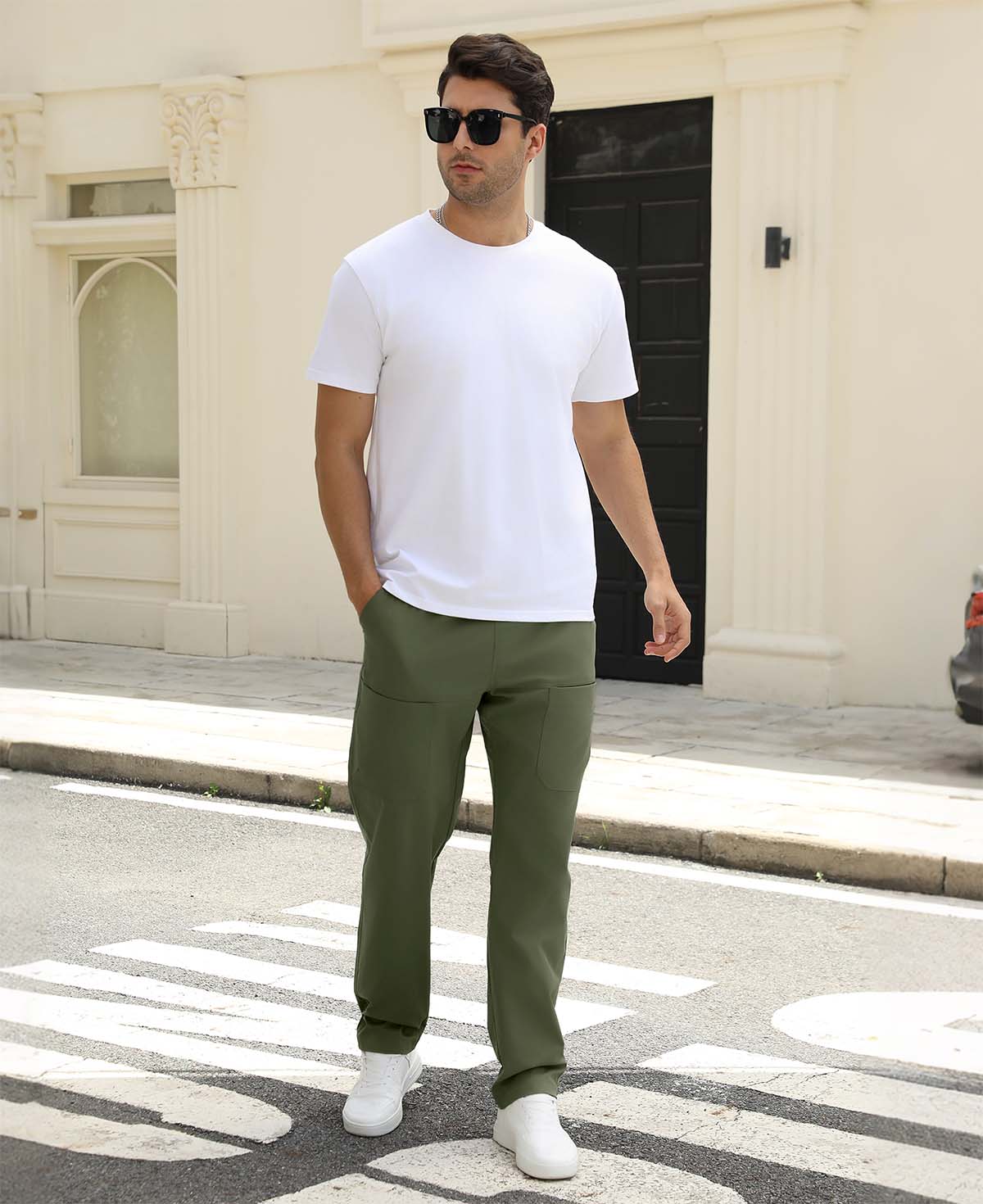 Man wearing white tee and green durable multipants standing on a street, hand in pocket, showcasing daily wear.