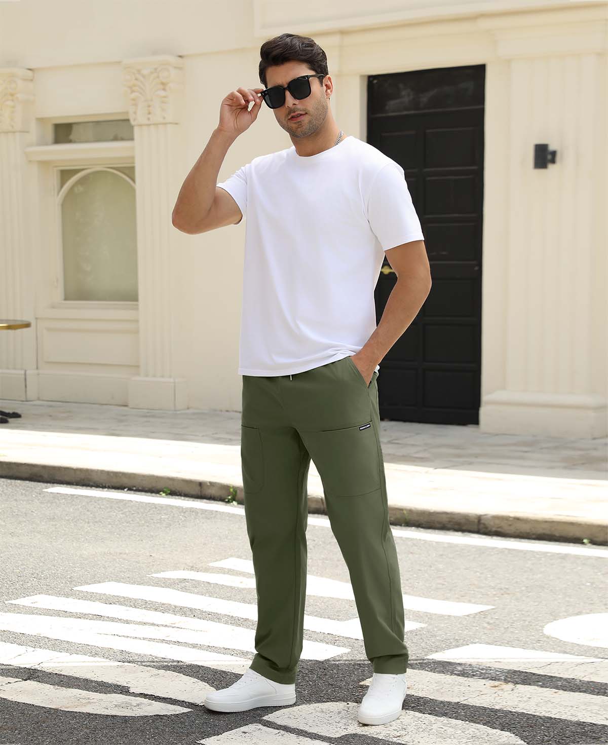 Man adjusting sunglasses, revealing side pocket details of green multipants, highlighting fit and pocket layout.
