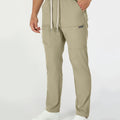 Man in khaki multipants with drawstring waist and multiple pockets, white sneakers, hand in pocket showing side logo.