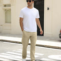 Man wearing white tee and khaki durable multipants standing on a street, hand in pocket, showcasing daily wear.