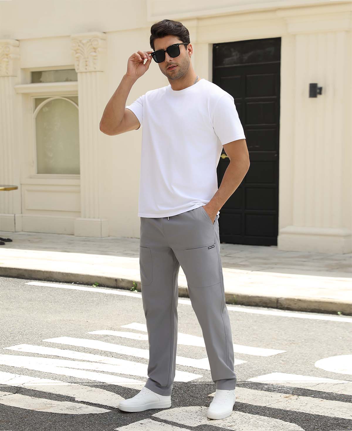 Man adjusting sunglasses, revealing side pocket details of light grey multipants, highlighting fit and pocket layout.