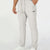 Man in white multipants with drawstring waist and multiple pockets, white sneakers, hand in pocket showing side logo.