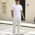 Man wearing white tee and white durable multipants standing on a street, hand in pocket, showcasing daily wear.