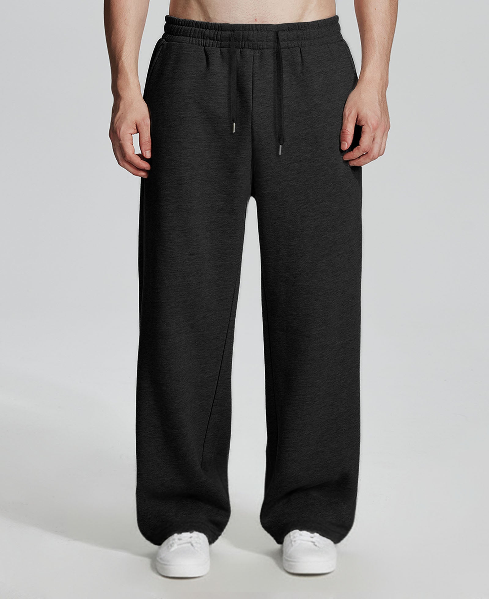 Model in black Men's Fleece Sweatpants ¨C Wide Leg Heavyweight Lounge Pants with white sneakers, showing drape and relaxed fit.
